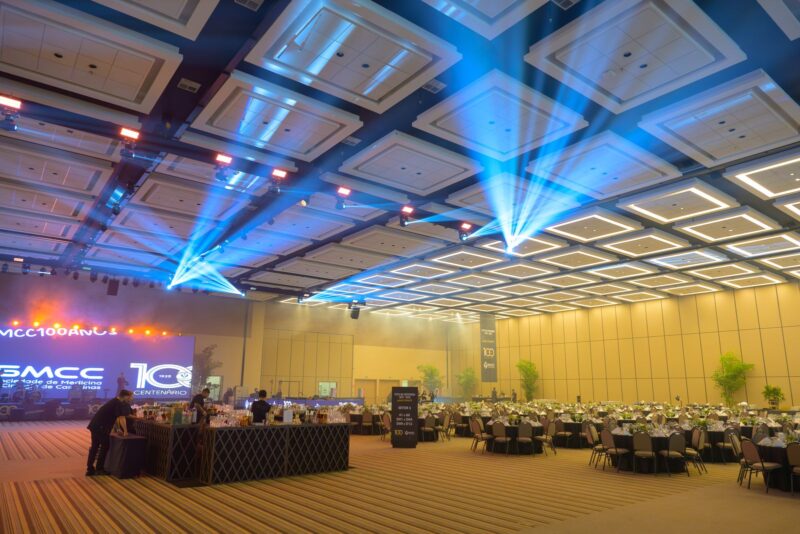 Salão do Royal Palm Hall com mesas e palco montados para a Festa do Centenário da SMCC